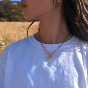 Unisex longhorn-style necklace combining a gold bull skull pendant with bold red cord.