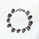 Delicate smokey quartz drop bracelet displayed on a white background, featuring sterling silver and silk cord.